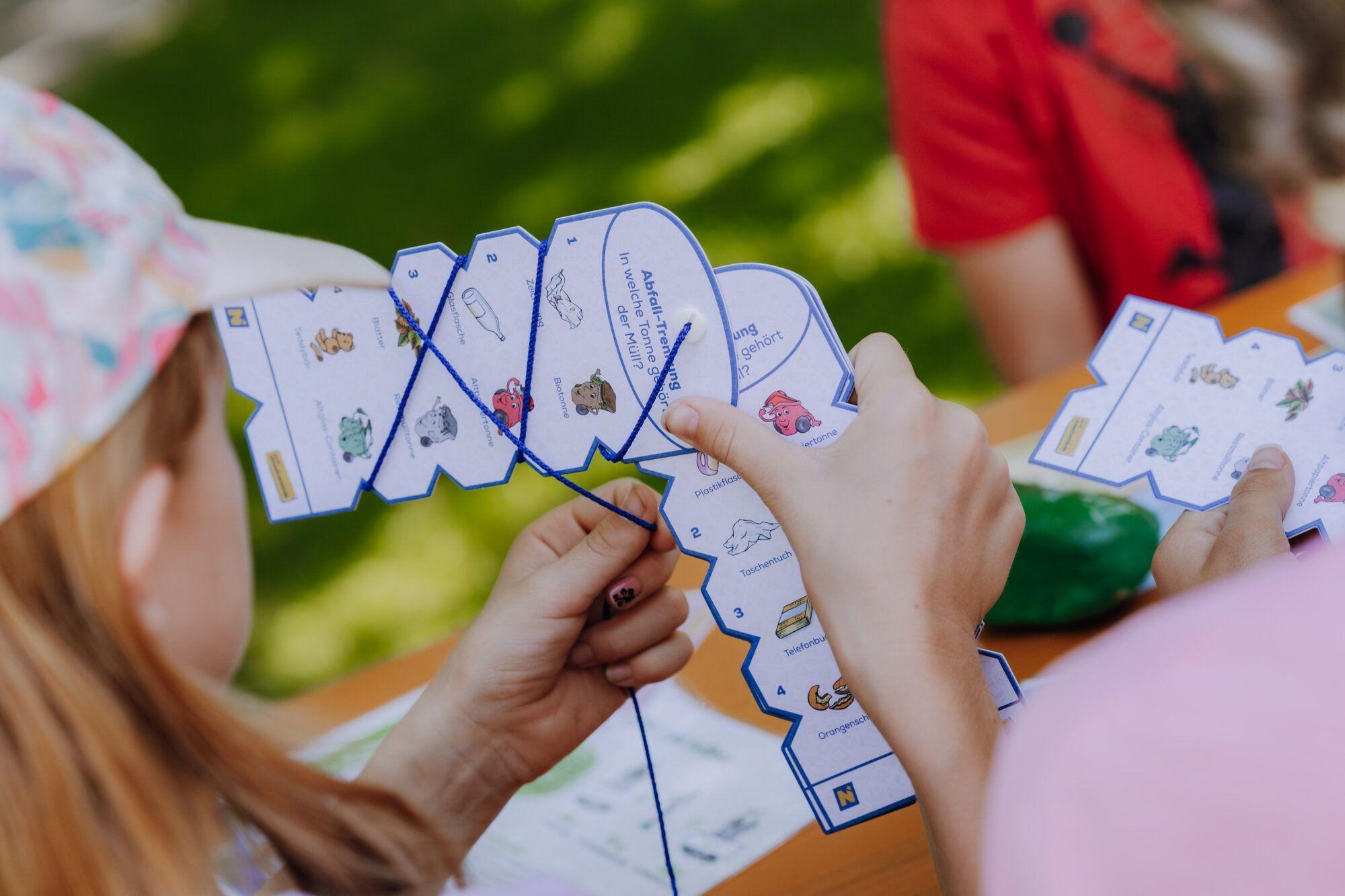 Ein Kind wickelt einen Faden um eine Kartonvorlage.